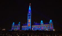 Photo of Centre Block lit up at night.